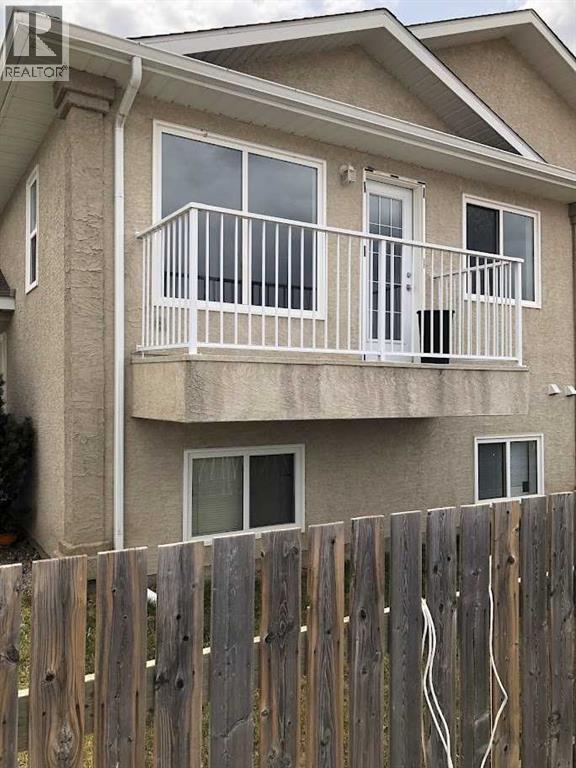 A two-story residential building with a balcony and a wooden fence in front.