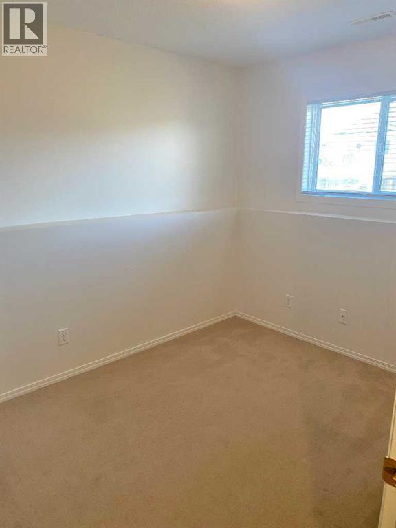 A room with a window and a carpeted floor.