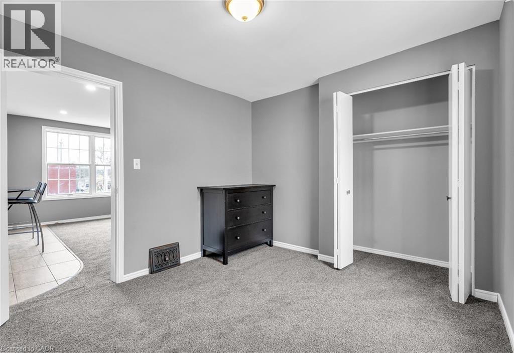 A bedroom with a black dresser and a grey carpet.