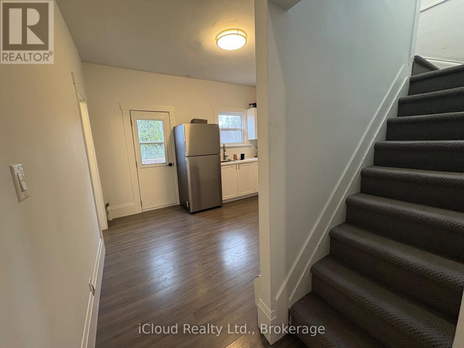 A staircase in a home with a refrigerator in the kitchen.