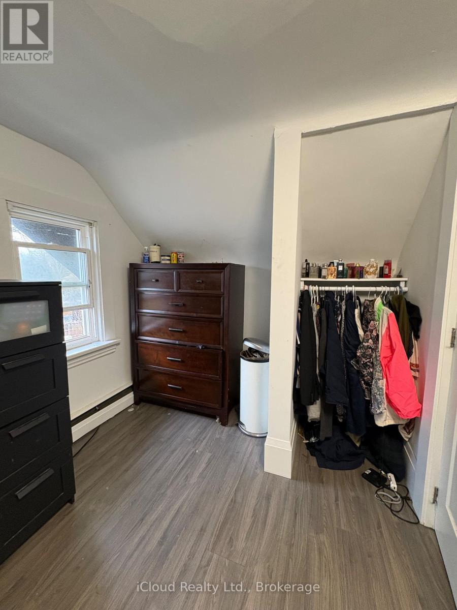 A bedroom with a wooden dresser and a closet with clothes.