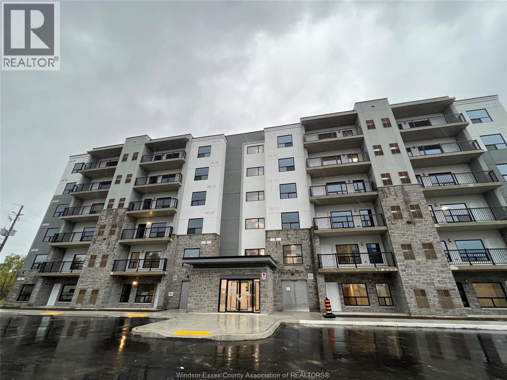 A large apartment building with a grey and white exterior and a puddle in front of it.