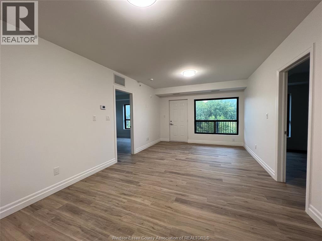 A spacious room with wooden flooring and white walls.