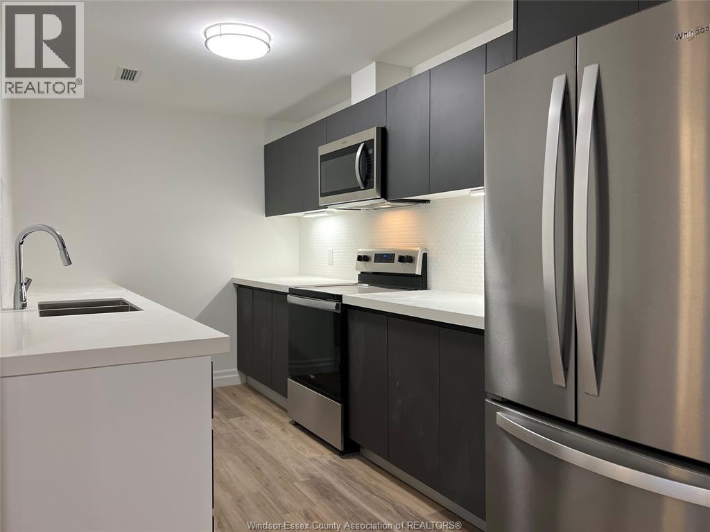 A kitchen with a stainless steel refrigerator, microwave, and oven.
