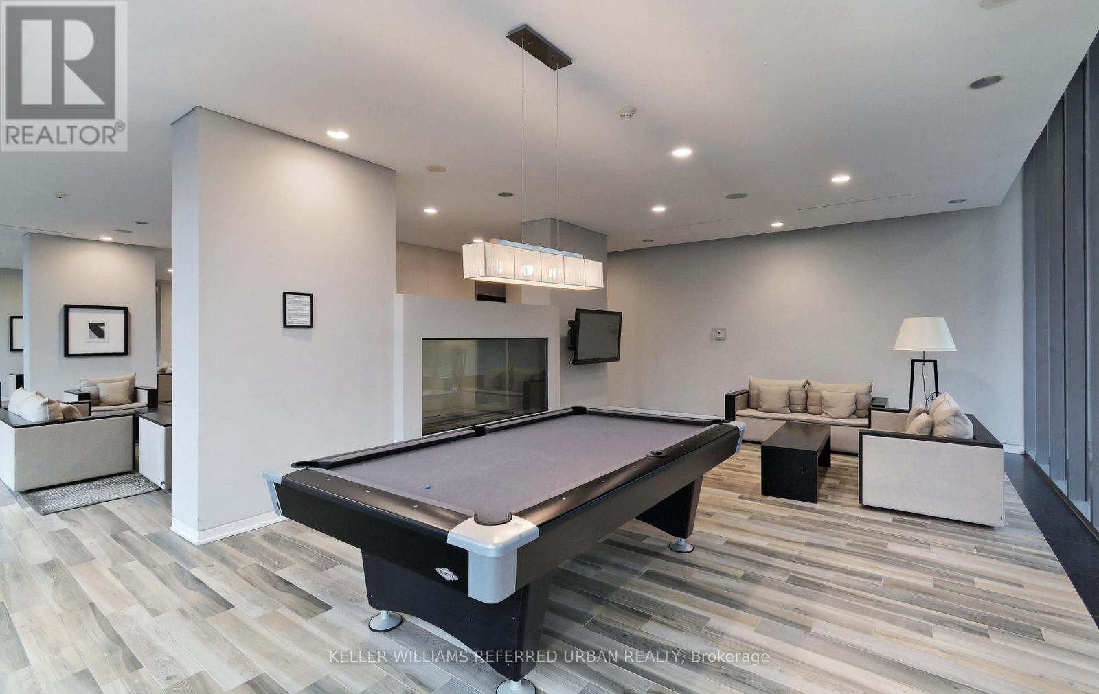 A pool table is in the middle of a room with a couch and a television.