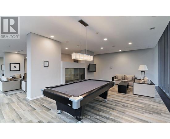 A pool table is in the middle of a room with a couch and a television.