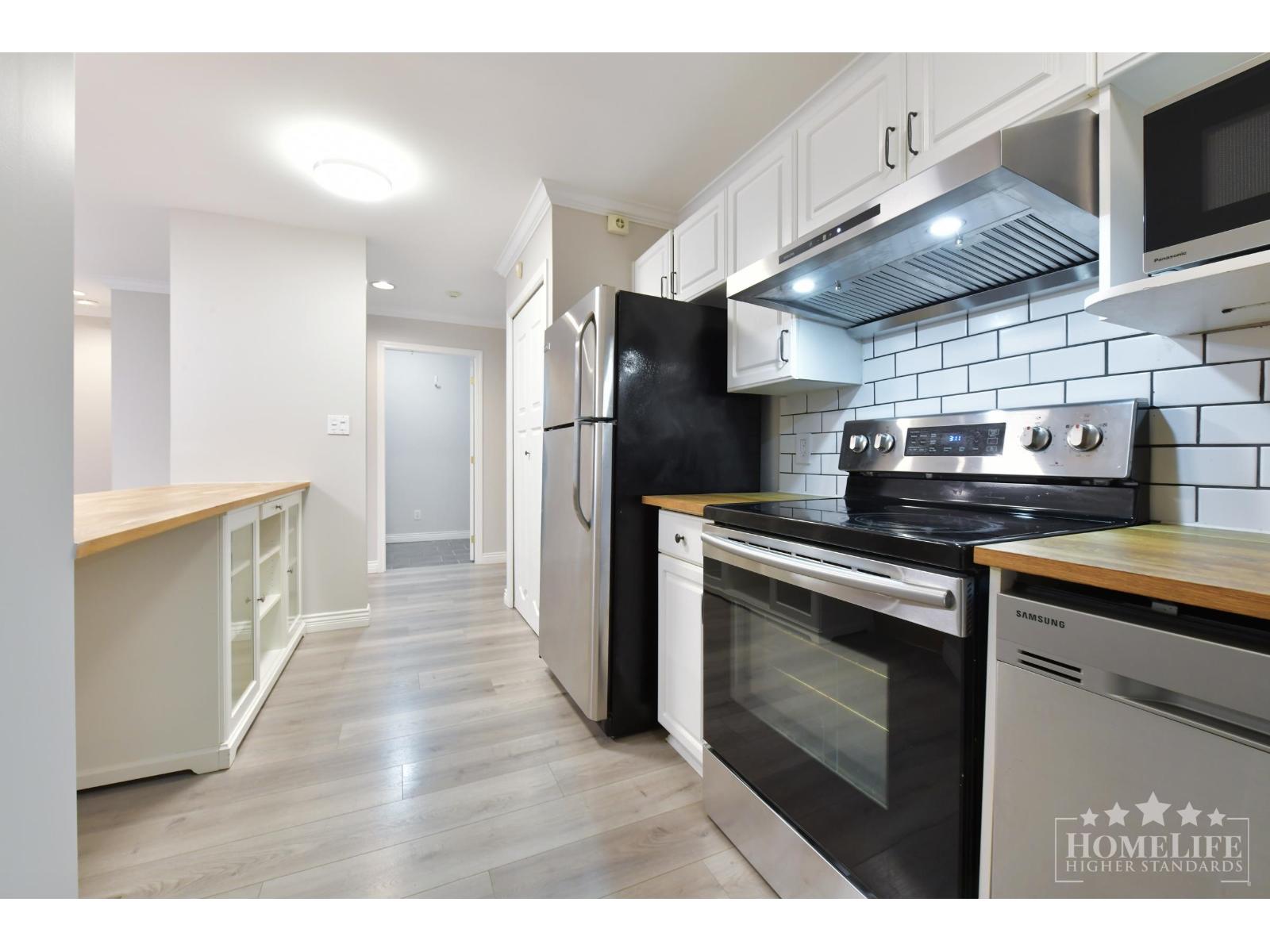 A kitchen with a black refrigerator and stove top oven.