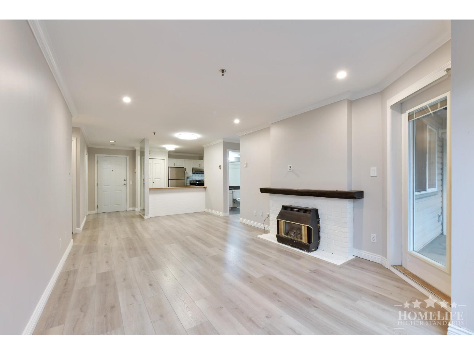 A spacious living room with a fireplace and hardwood floors.