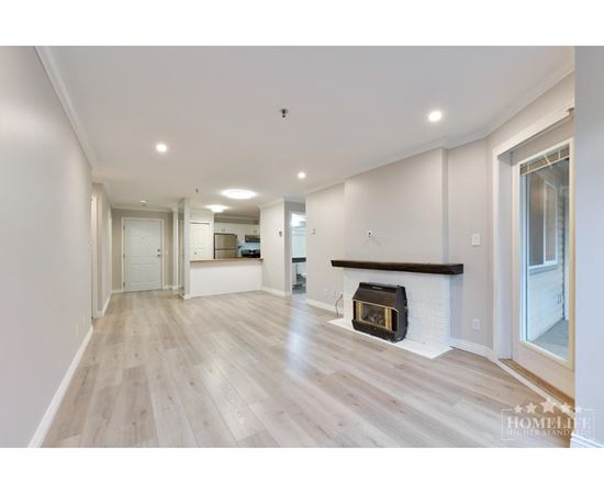 A spacious living room with a fireplace and hardwood floors.