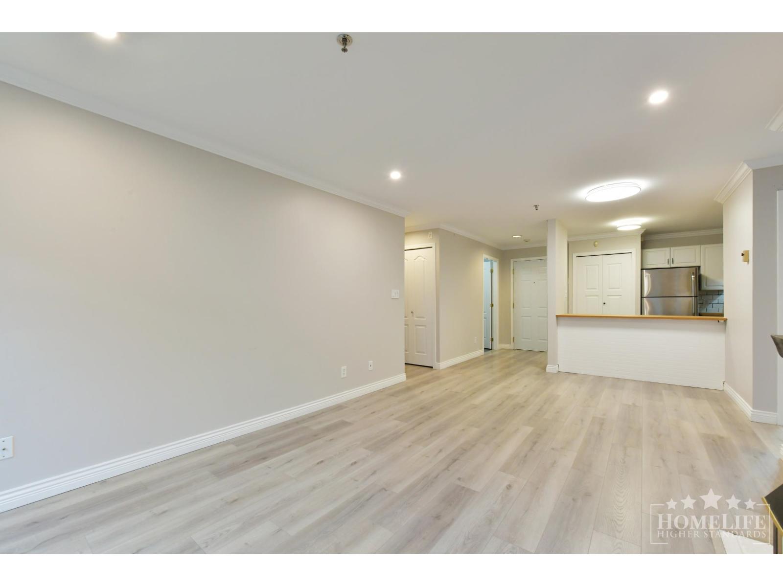 A spacious room with wooden flooring and white walls.