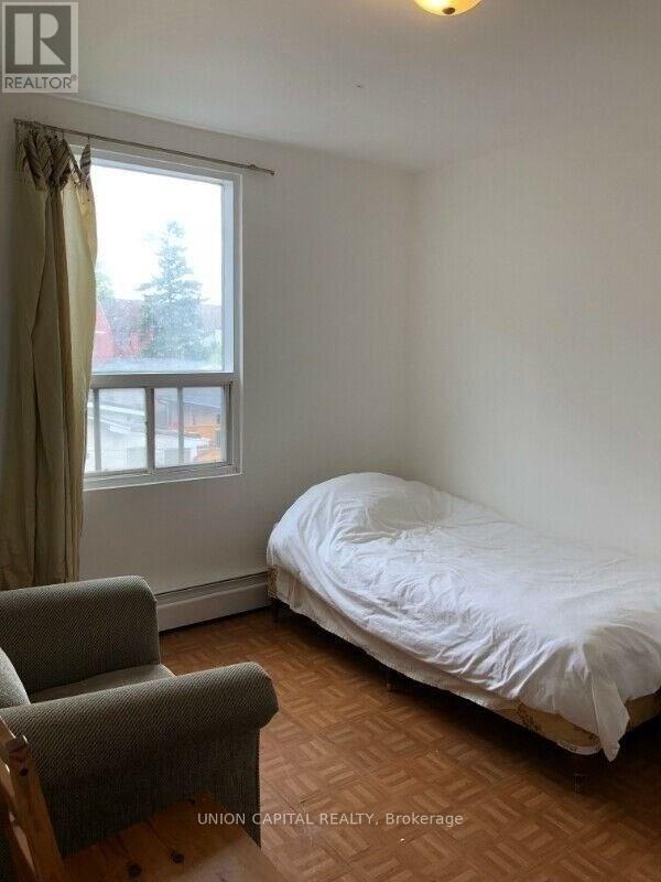 A bedroom with a bed, chair, and window.