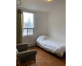 A bedroom with a bed, chair, and window.