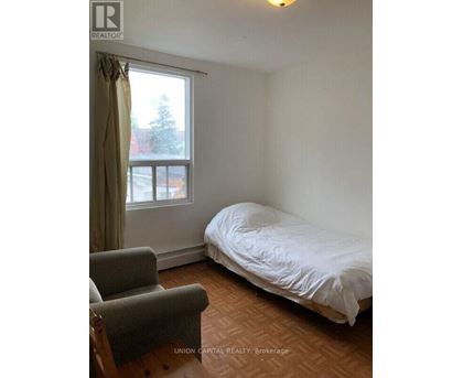 A bedroom with a bed, chair, and window.