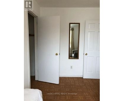 A bedroom with a bed, mirror, and two doors.