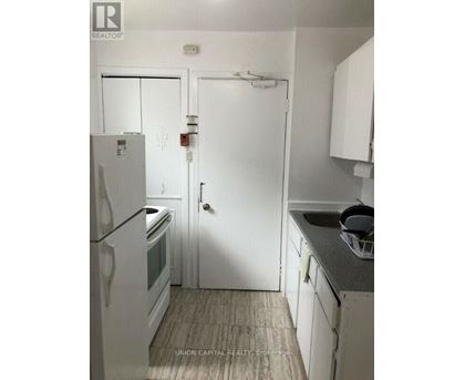 A kitchen with a white fridge and white cupboards.