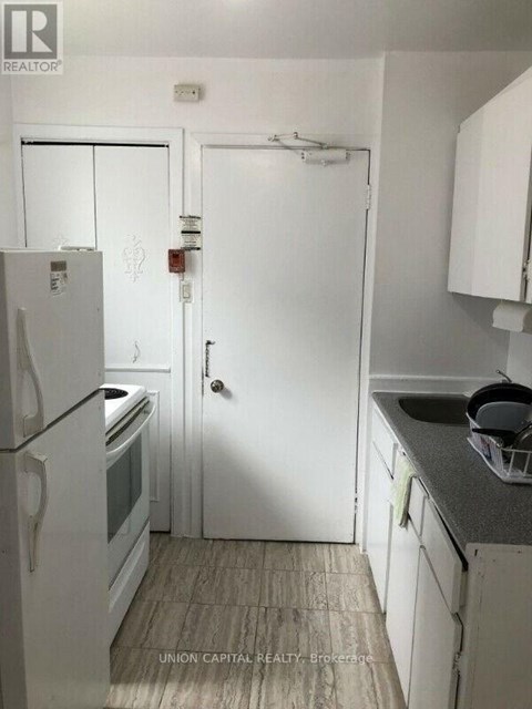 A kitchen with a white fridge and white cupboards.