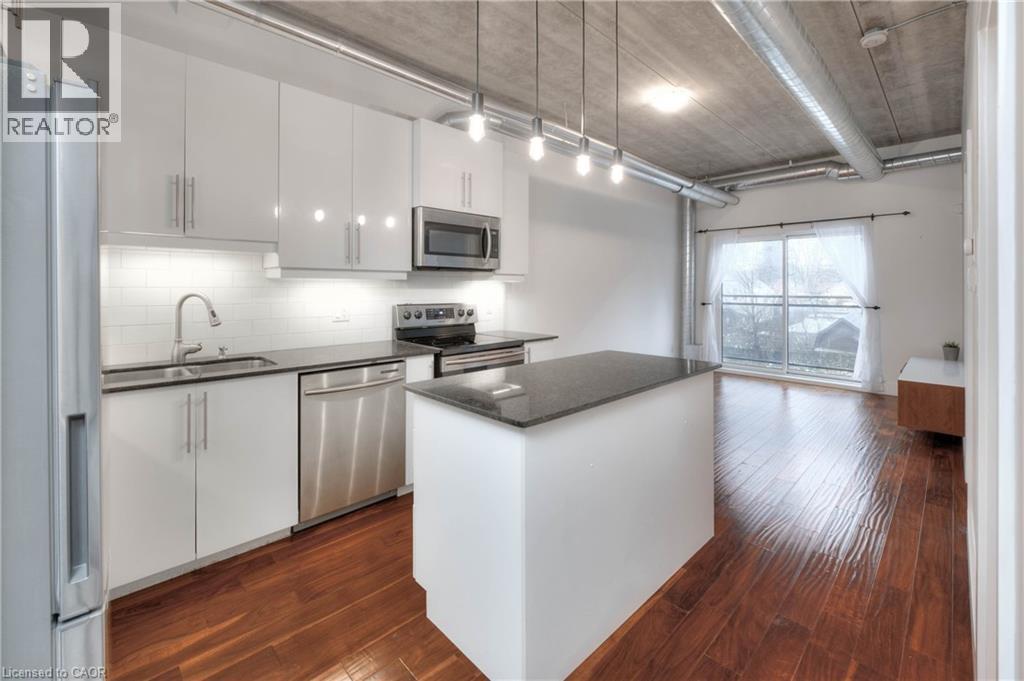 A modern kitchen with white cabinets and a wooden floor.