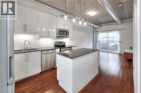 A modern kitchen with white cabinets and a wooden floor.