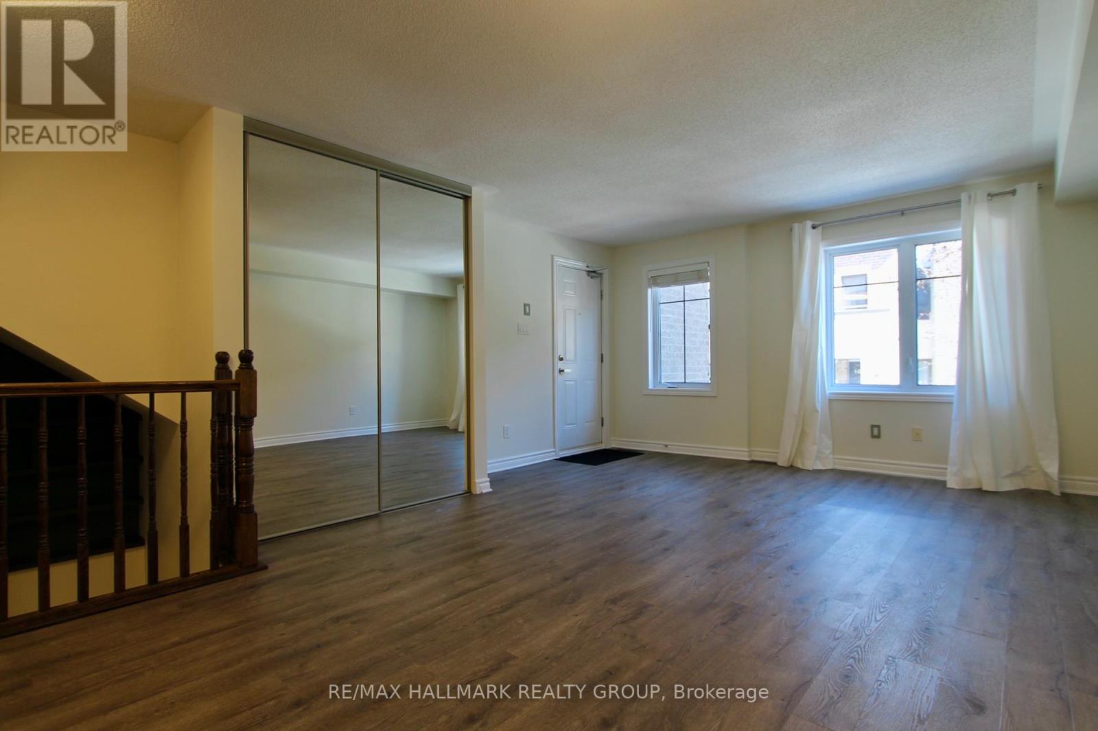 A spacious room with wooden floors and a glass door leading to another room.