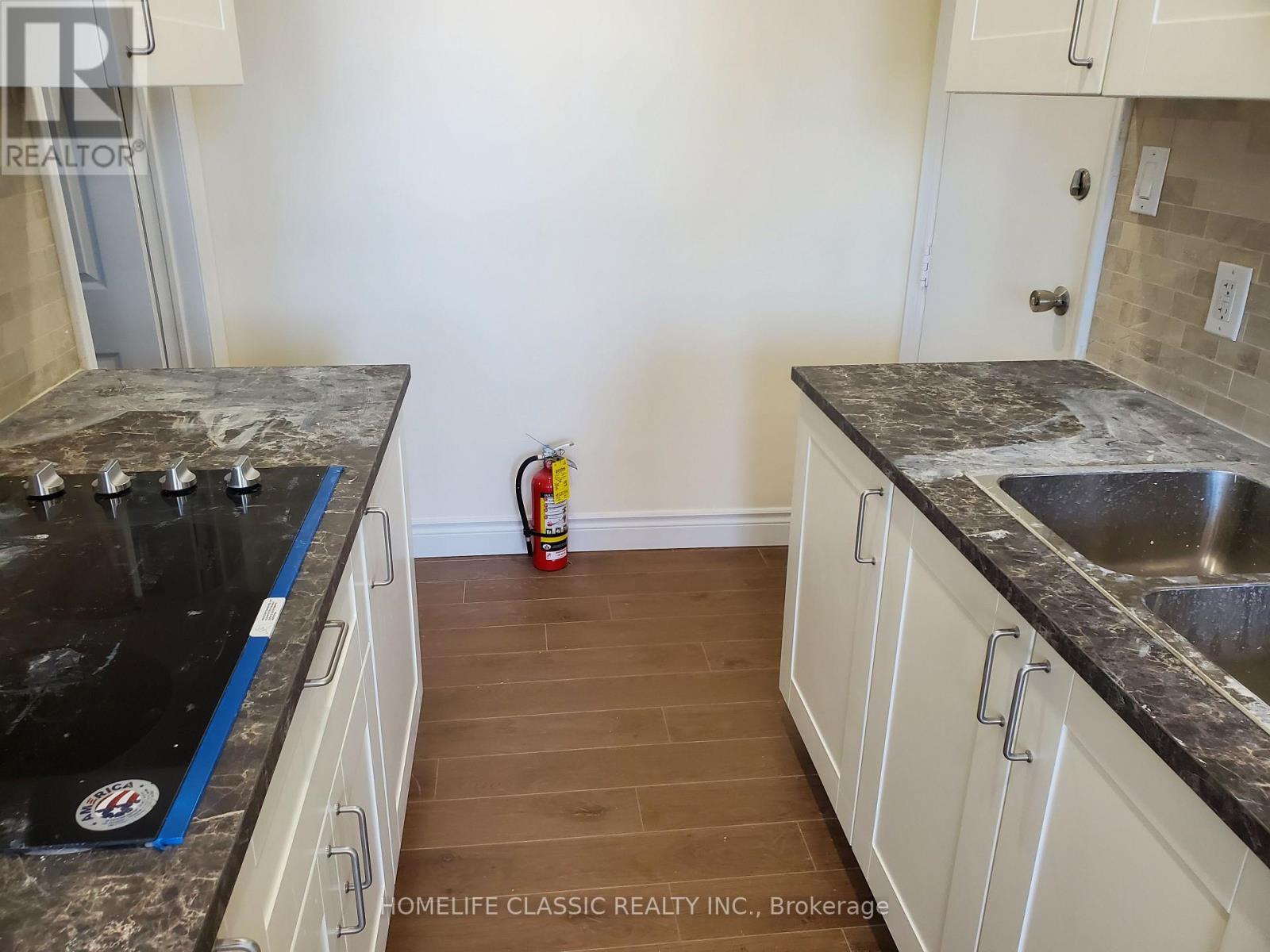 A kitchen with white cabinets and a black counter top.