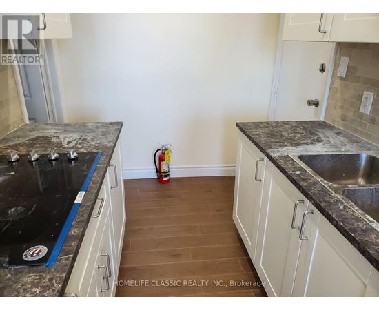 A kitchen with white cabinets and a black counter top.
