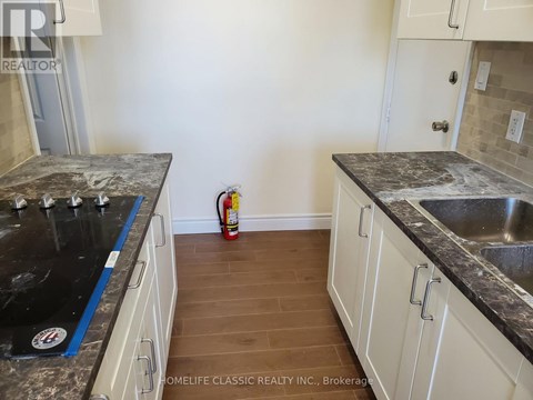 A kitchen with white cabinets and a black counter top.
