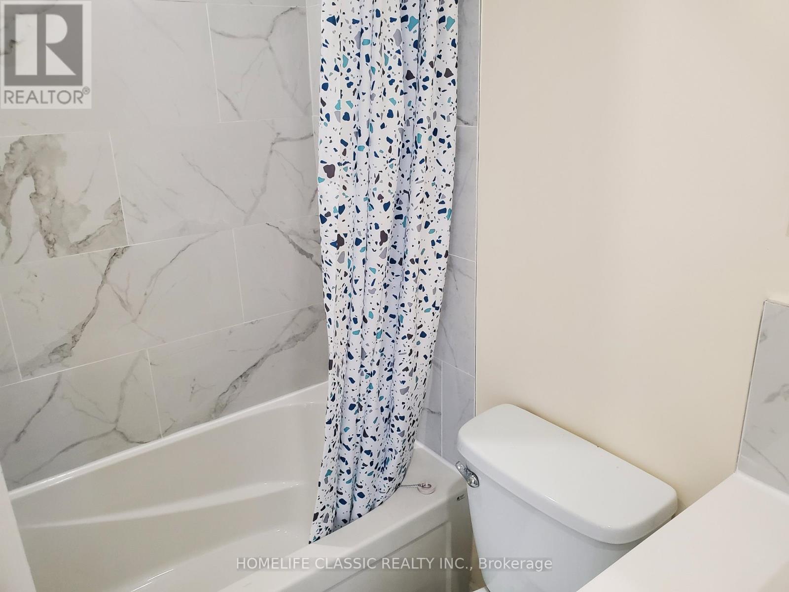 A white toilet sits next to a bathtub in a bathroom.