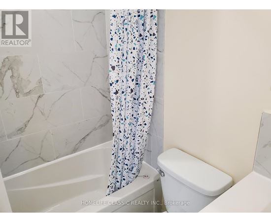 A white toilet sits next to a bathtub in a bathroom.