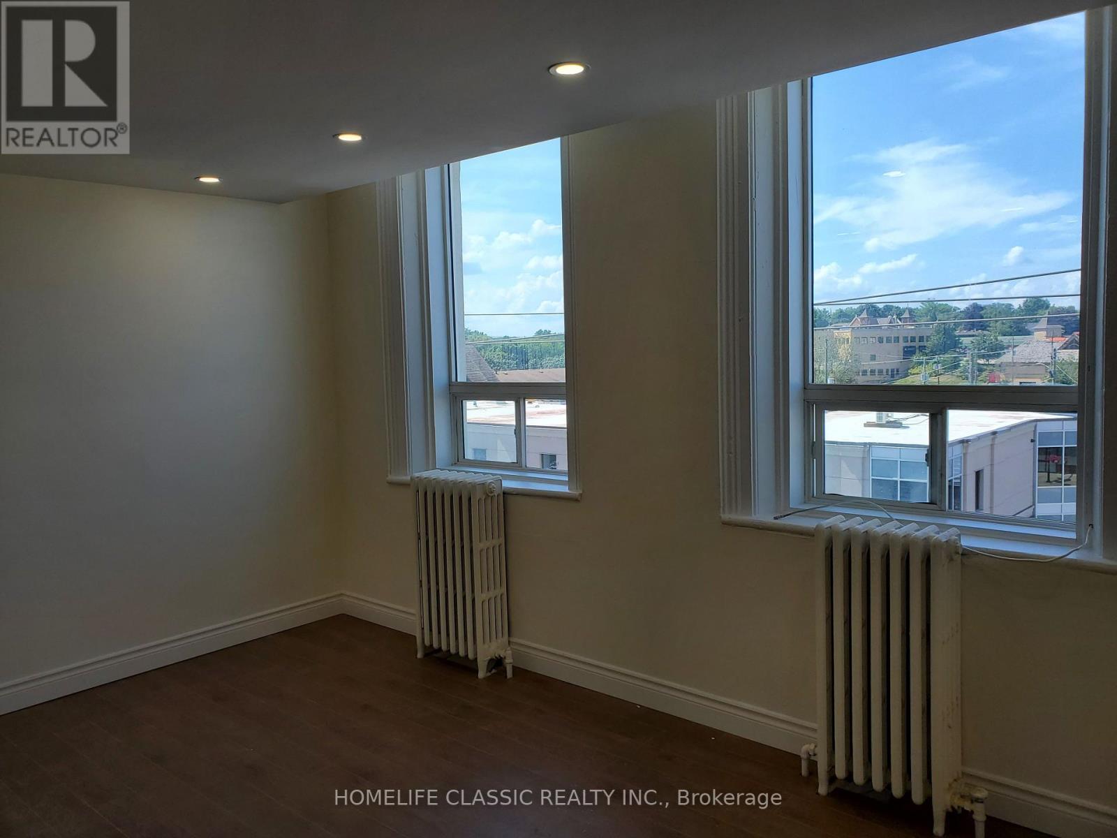 A room with two windows and a radiator on the floor.