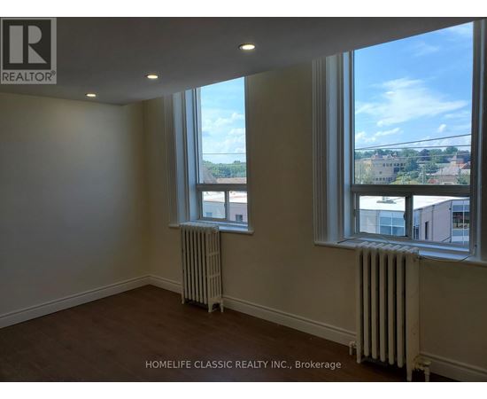 A room with two windows and a radiator on the floor.