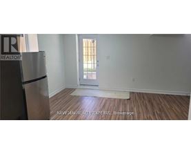 A room with a wooden floor and a white wall with a doorway leading to a balcony.