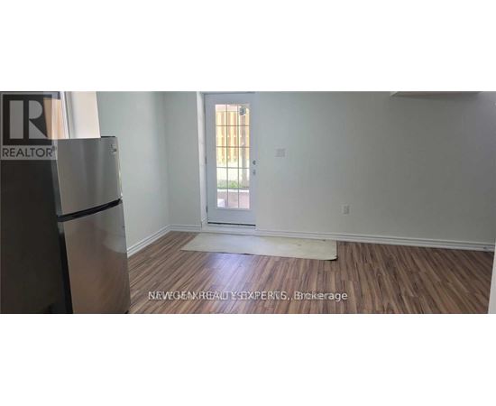 A room with a wooden floor and a white wall with a doorway leading to a balcony.