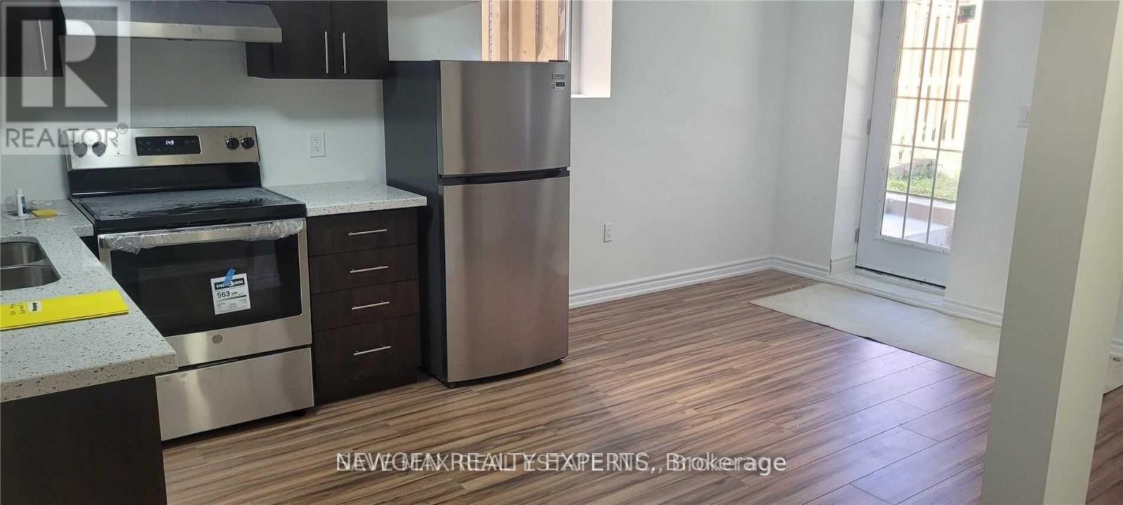 A kitchen with a stainless steel refrigerator and wooden flooring.