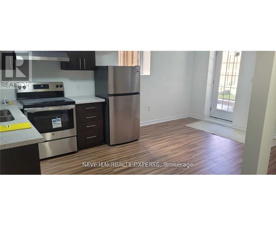 A kitchen with a stainless steel refrigerator and wooden flooring.