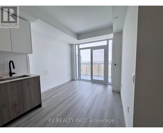 A spacious room with a sink and wooden flooring.