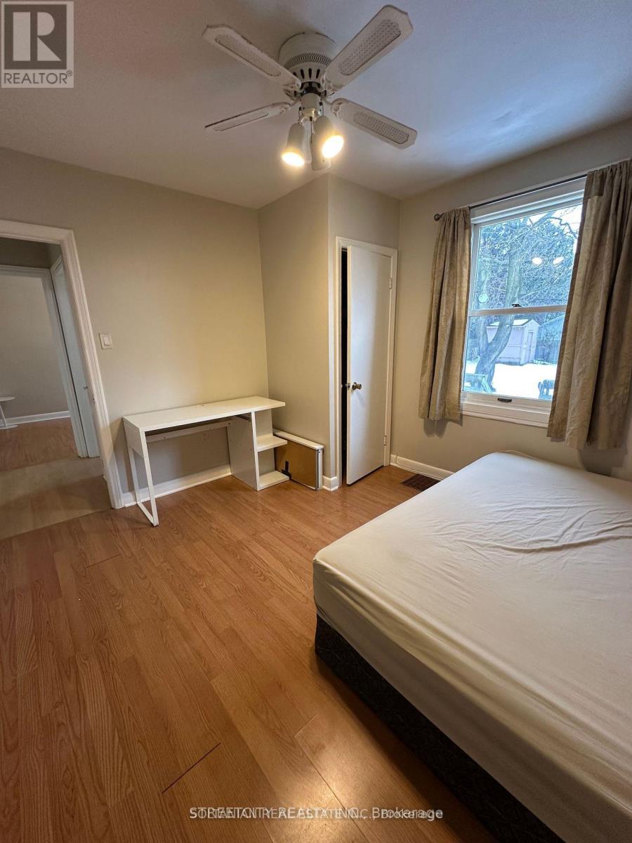 A bedroom with a bed, desk, and window.