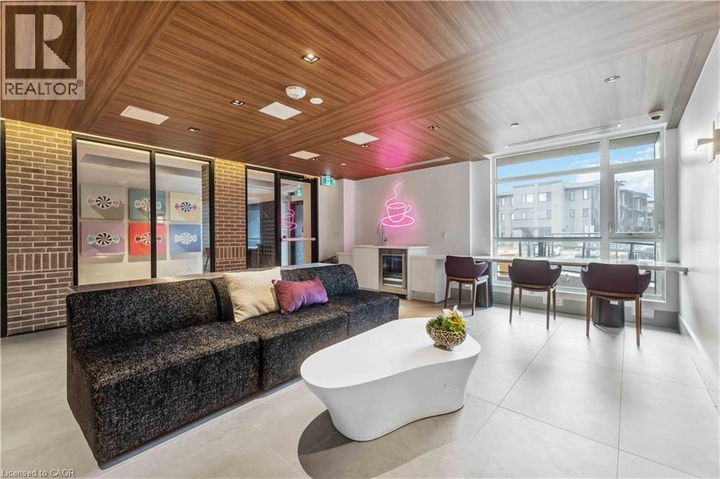 A modern living room with a grey sofa and a pink neon sign.
