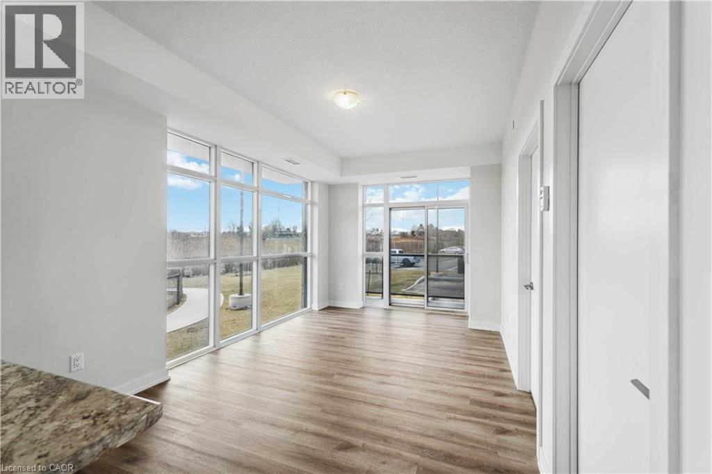 A spacious room with wooden flooring and large windows.