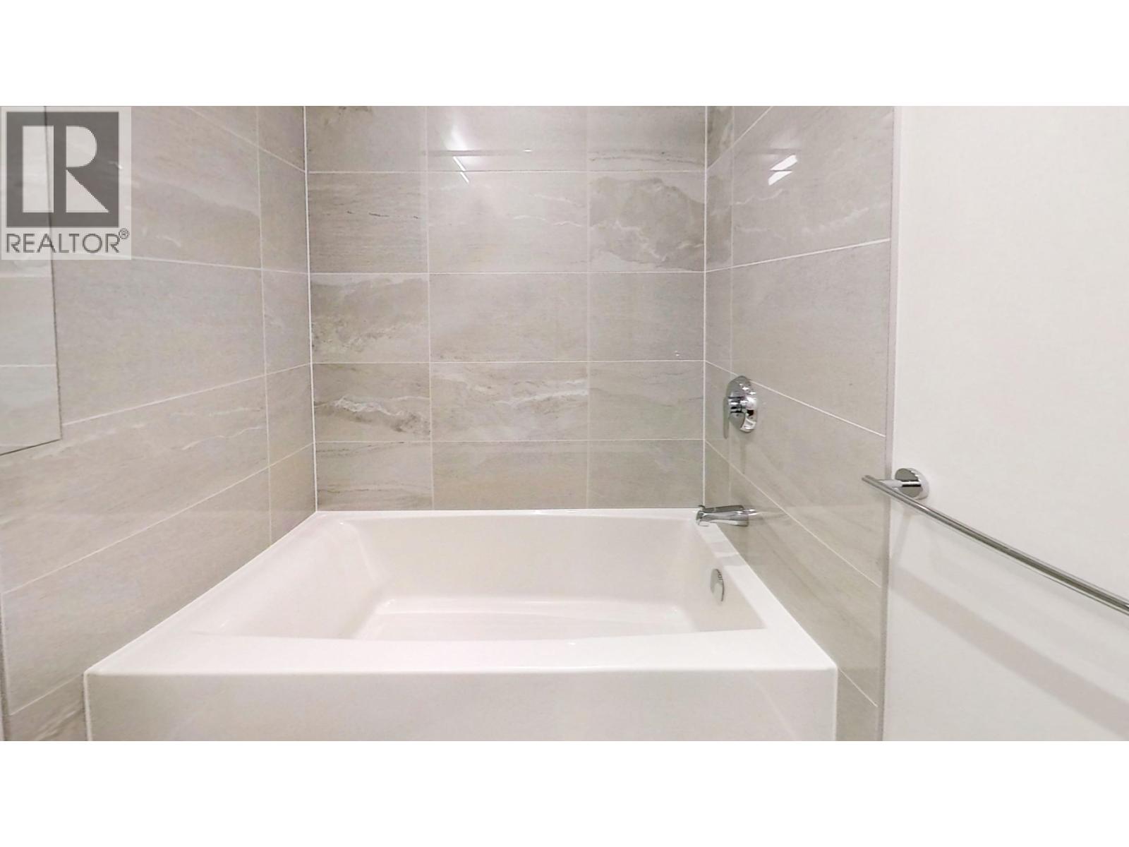 A white bathtub in a bathroom with tiled walls.