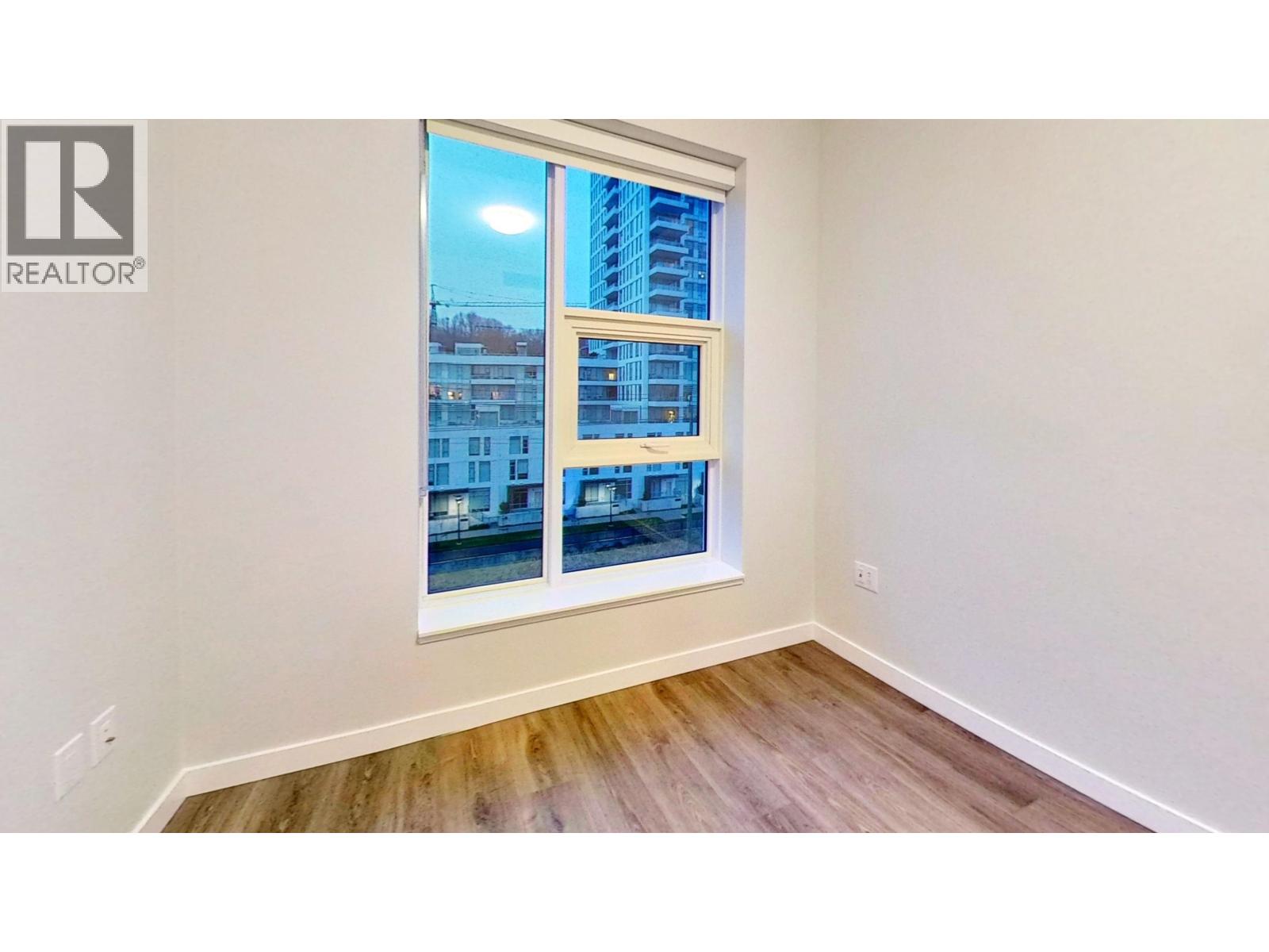 A room with a window showing a view of a building.