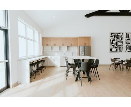 A modern dining room with a white table and black chairs.