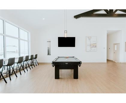 A pool table is in the middle of a room with a tv and chairs.