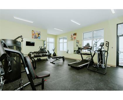 A gym with a variety of equipment including treadmills, weights, and exercise machines.