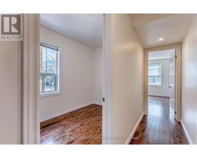 A room with wooden floors and white walls, with a window and a door visible.