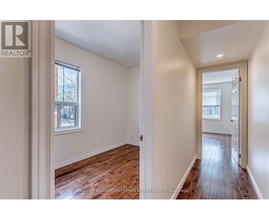 A room with wooden floors and white walls, with a window and a door visible.