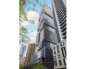 A tall building with a glass facade stands in front of other buildings.