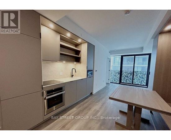 A modern kitchen with a wooden table and stainless steel appliances.