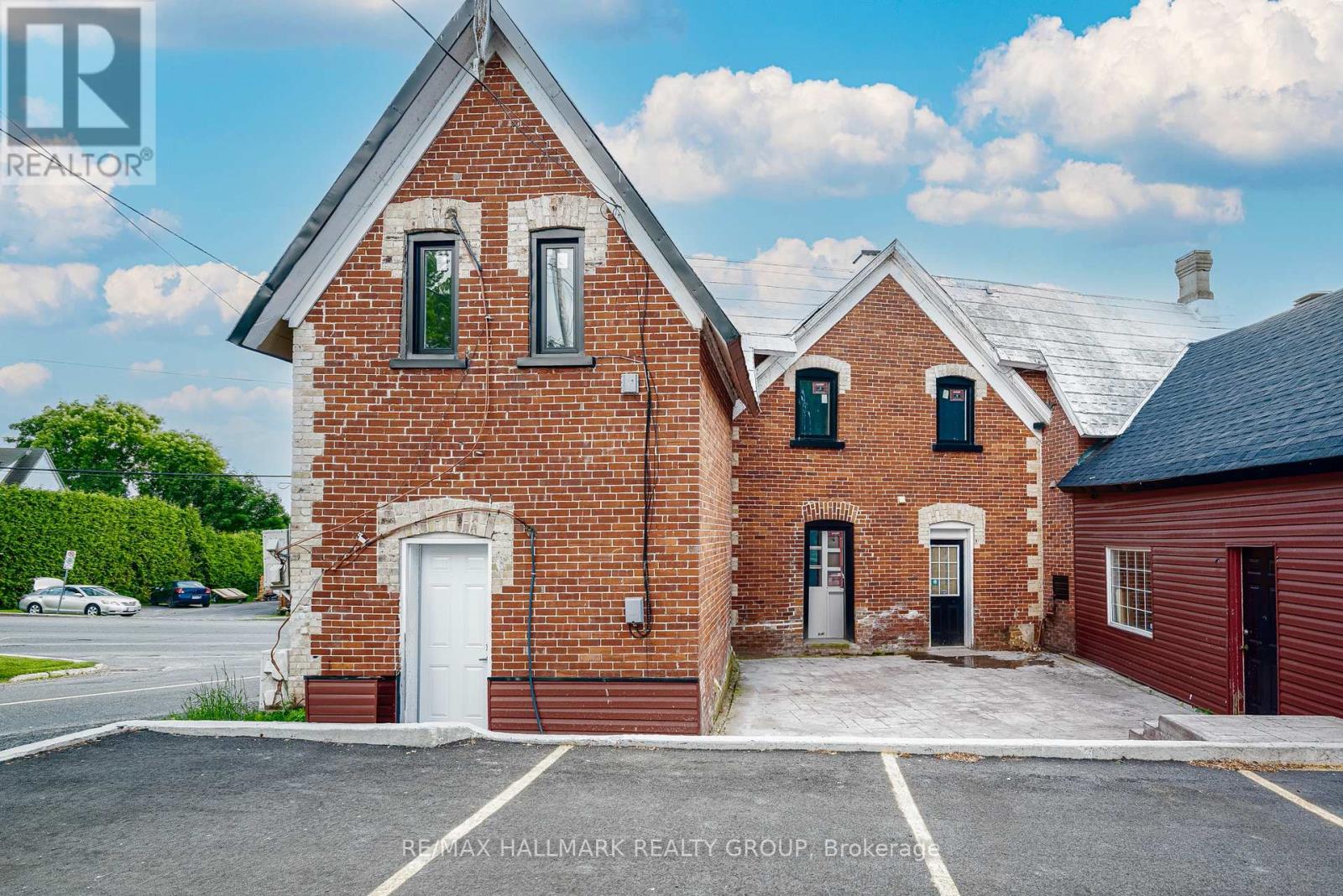 A red brick building with a white door and windows is for sale.