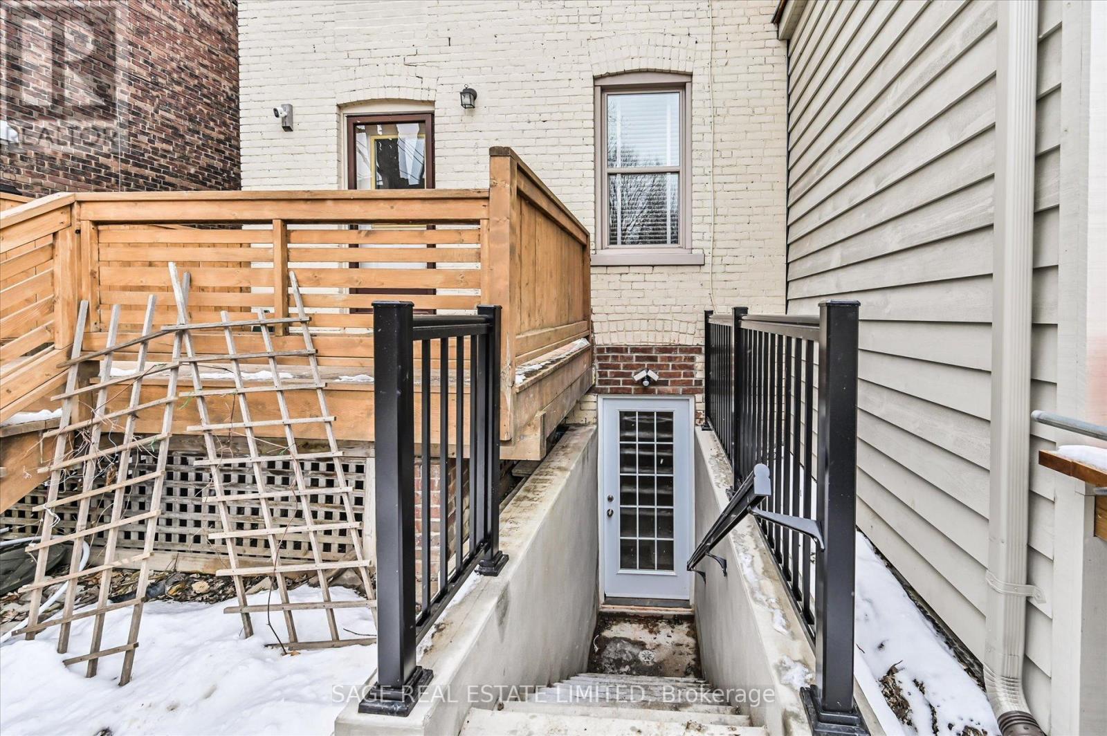 A wooden deck with a black railing is in front of a building.