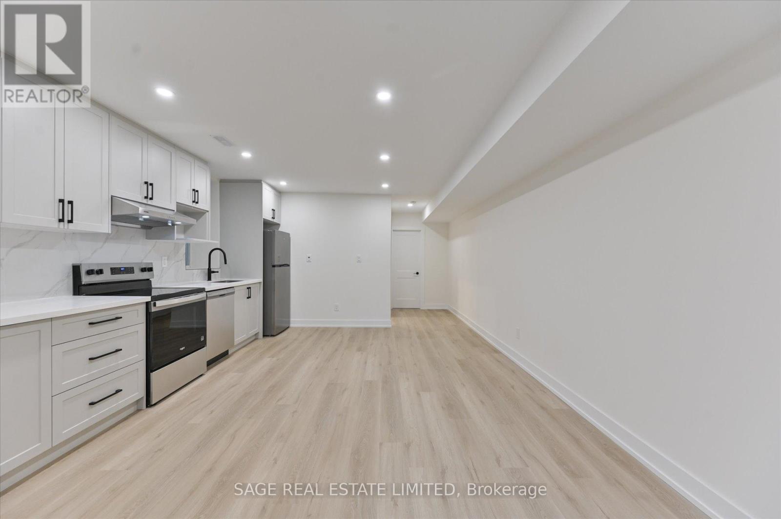 A kitchen with white cabinets and appliances in a white room.